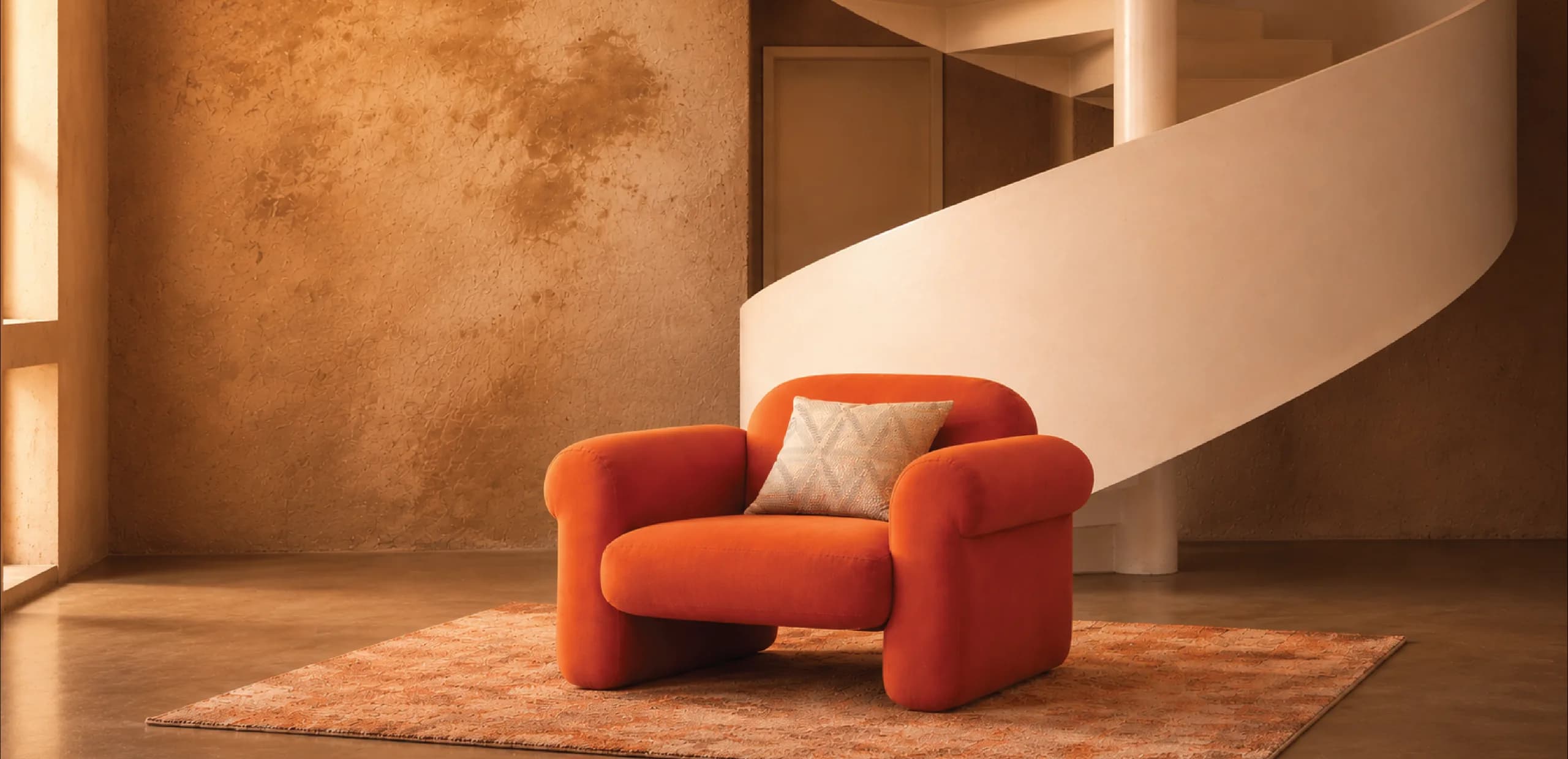 An orange armchair beneath a sculptural spiral staircase